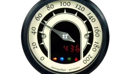 The image shows a front view of the Motogadget MST Speedster Gauge with lights on.